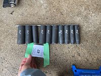 Top view of the 10 black heavy duty sockets arranged in a row on concrete.