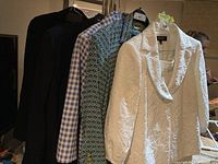 Three ladies suit jackets hanging together, showing a black jacket, a blue and white checked jacket, a blue and green geometric patterned jacket, and a white textured Kasper jacket with large lapels.