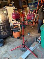 Full view of double red metal LED work lights on tripod, showing setup in garage with surrounding items.