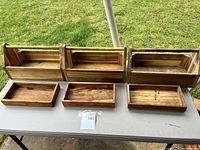 Three wooden tool boxes and their removable trays displayed on white table outdoors. Natural wood grain is visible. Used lightly with minor wear.