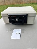 Front view of off-white SentrySafe 1100 fireproof safe with black handle and lock, key inserted.