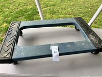 Top view of blue furniture dolly showing black non-slip pads on each end and central handle hole.