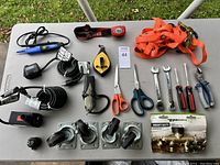 Full view of tools including wrenches, scissors, power tools, strap, and caster wheels on table.