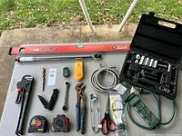 Wide view of all tools spread out on a concrete and table surface, showing the assortment and condition