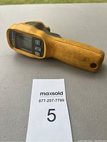 Full side view of the yellow Fluke 62 MAX+ infrared thermometer resting on a flat surface.