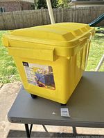 Yellow storage trunk on wheels placed on table outdoors, showing front and handle.