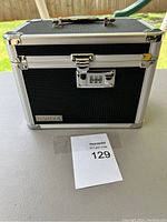 Closed black Yahtu lock box on table outdoors with vendor lot number card in front.