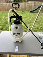 Full view of Chapin HomePro pump sprayer on table outdoors showing white translucent tank, black top, and hose coiled up.