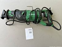 Full view of green and black Metabo HPT reciprocating saw with cord coiled around it.