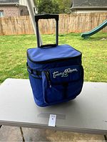 Front angled view of the blue Tommy Bahama rolling cooler with black retractable handle extended