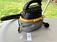 Full side angle view of Stinger wet/dry shop vacuum with hose and power cord, placed on a table outdoors.