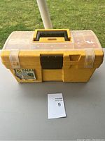 Closed yellow Stanley plastic toolbox showing handle, latches, and 6OME label.