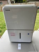 Front view of Toshiba dehumidifier showing water level indicator and brand logo.