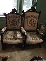 Pair of antique chairs side by side. Both have ornately carved wooden frames and floral tapestry upholstery. The rocker is on the right with curved wooden rockers visible.