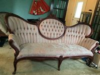 Full view of the antique Victorian style sofa showing its broad curved back and wood frame with brocade upholstery.
