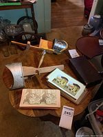 Overview of two stereoscopes, stack of photo cards, and carrying box on table