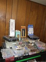 Overall view of top shelf with clear storage boxes, black toolboxes and packaged bead kits