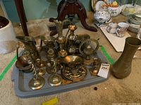 Wide angle view showing all brass items on a tray including pitchers, candle holders, twisted candlesticks, and a wall plaque.