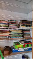 Photo showing multiple shelves holding stacks of children's books and several boxed board games.