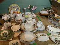 Wide view of all dishware and items on carpet including lidded vegetable dishes, Adams and Sons bowls, tea cups, plates, and crystal vase with porcelain flowers