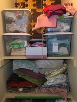 Wide shot of the shelving with two shelves filled with plastic totes and stacked fabric pieces.