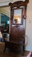 Front view of entire hall tree showing carved top crest, mirror and bench seat