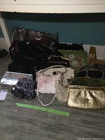 Overall view of eleven vintage ladies purses grouped on a carpet showing variety of colors, designs and materials.