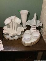 Full view of milk glass collection including Fenton hobnail epergne, vase, teacups with plates, and ruffle basket