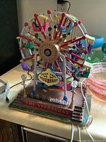 Full view of colorful animatronic Ferris wheel on a detailed base with stairs and signage.