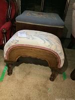 Two upholstered ottomans one with a floral fabric upholstery and one with needlepoint upholstery, both with wood frames and turned legs