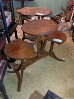 Front and side view of the wooden stand showing three shelves - central round, smaller round, and semi-circular side shelf, with carved legs and claw feet.