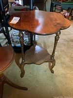 Front angled view showing the unique scalloped wooden top with wood grain details and three curved legs.