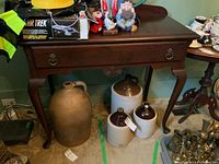 Overall view of the solid wood hall table showing drawer and curved legs, with scratch marks visible on top surface. Various items placed on and around table, not included.