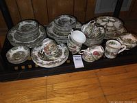 Full set of Johnson Bros. The Friendly Village china pieces arranged showing plates, cups, saucers, bowls, and serving items.