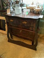 Full view of the dark wooden wash stand with drawer and cupboard, showing wood grain and brass hardware.