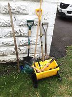 Overall view of yard tools including shovel, fork, rakes, salt and sand spreader, roof rake head only