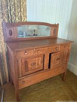 Front view of antique wooden server with mirror, showing 4 drawers and 2-door cupboard with wooden knobs.