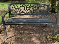 Front view of metal bench showing decorative openwork backrest and slatted seat