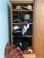 Full view of wooden shelf with assorted hats, purses, wallets, scarf, gloves, and umbrella visible on and around shelves.
