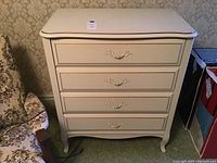 Front view of dresser showing four drawers with ornate metal drawer handles and curved legs.