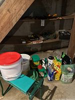 Wide shot of gardening supplies showing buckets, Miracle-Gro containers, potting soil bags, green metal bench.