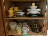 Overview of two shelves with FiestaWare, Fire King, Johnson Bros pieces and glass bowls