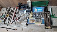 Full view of the collection of hand tools on a table including wrenches, ratchets, sockets, and the power stapler.
