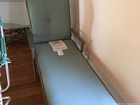 Full front view of the lounge chair showing grey metal frame and teal cushion with button tuft.