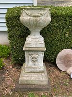 Front view of the concrete planter seated on the pedestal, showing overall form and gargoyle detail