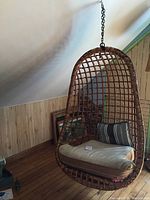 Full view of rattan egg chair hanging in room showing shape and cushion placement