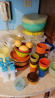 Photo showing large bowls with lids, multi-colored plates, popsicle molds, stacking cups and some round containers with lids