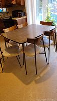 Rectangular table with woodgrain melamine top and six chairs in kitchen setting.