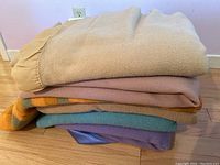 Side view showing stack of six wool blankets in various colors and textures.