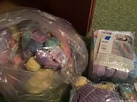 Plastic bag containing assorted pastel colored wool yarn skeins: purple, yellow, mint green, and others.